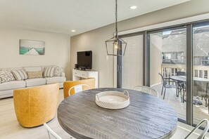 A modern living room with a round wooden table, a sofa, and a TV.