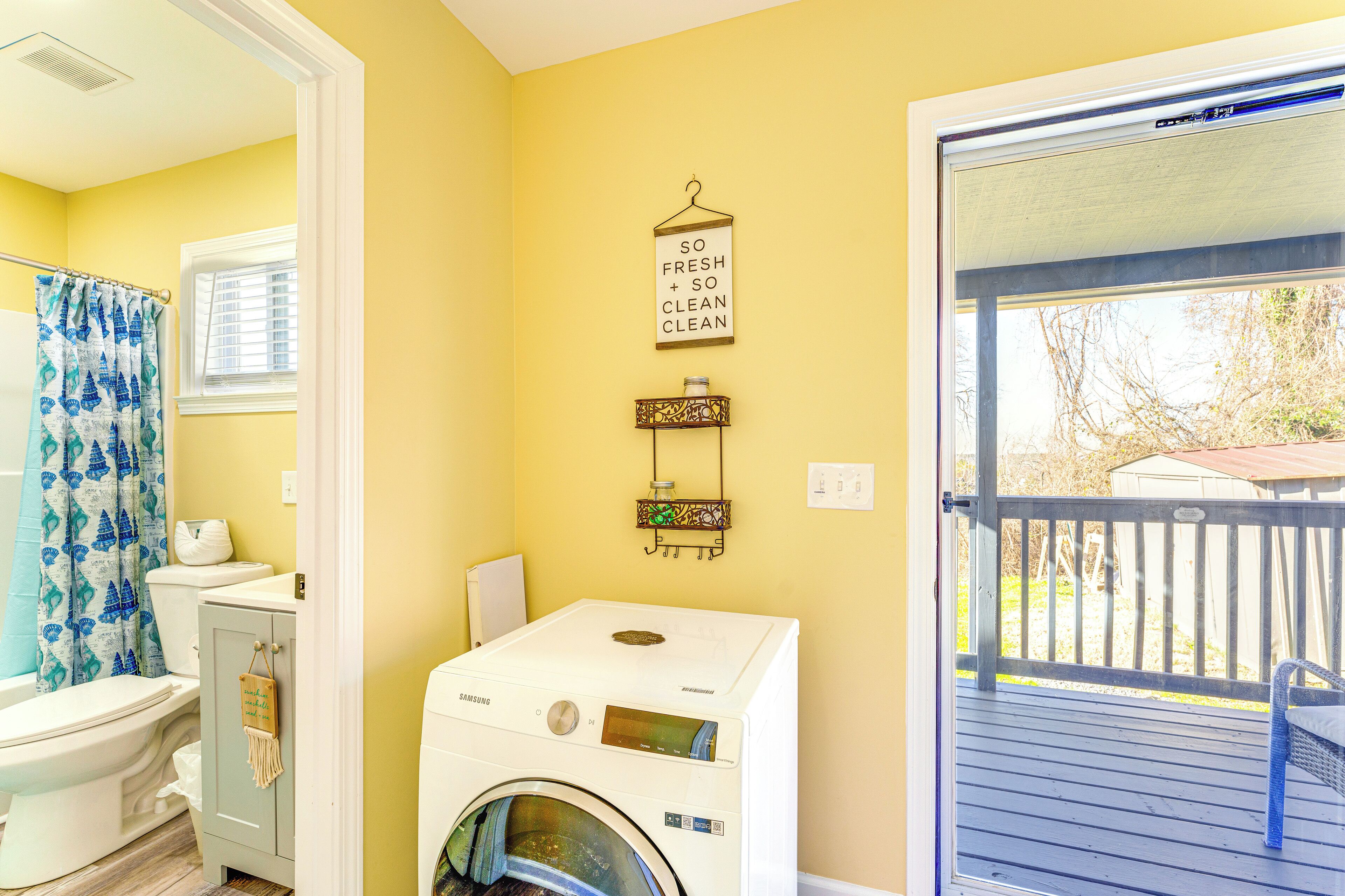 A compact bathroom with a white toilet, a washing machine, and a blue shower curtain.
