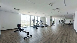 Une salle de sport spacieuse équipée de machines de cardio, de matériel de musculation et de grandes fenêtres donnant sur l’extérieur.