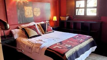 Un dormitorio con una cama grande, una mesita de noche, una lámpara, una ventana y techo de madera.