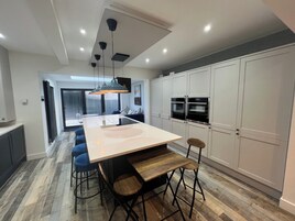 Una cocina moderna con una isla central, taburetes de bar y hornos empotrados.