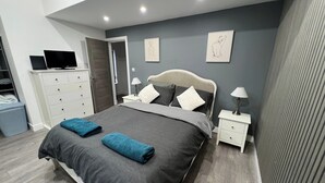 Un dormitorio moderno con cama, mesitas de noche, televisor y armario.