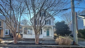 A two-story house with a porch, a green door, and a brick chimney. - 112 S Washington Avenue (Lewes)