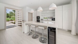 Een moderne keuken met witte kasten, roestvrijstalen apparatuur en een groot kookeiland met barstoelen.