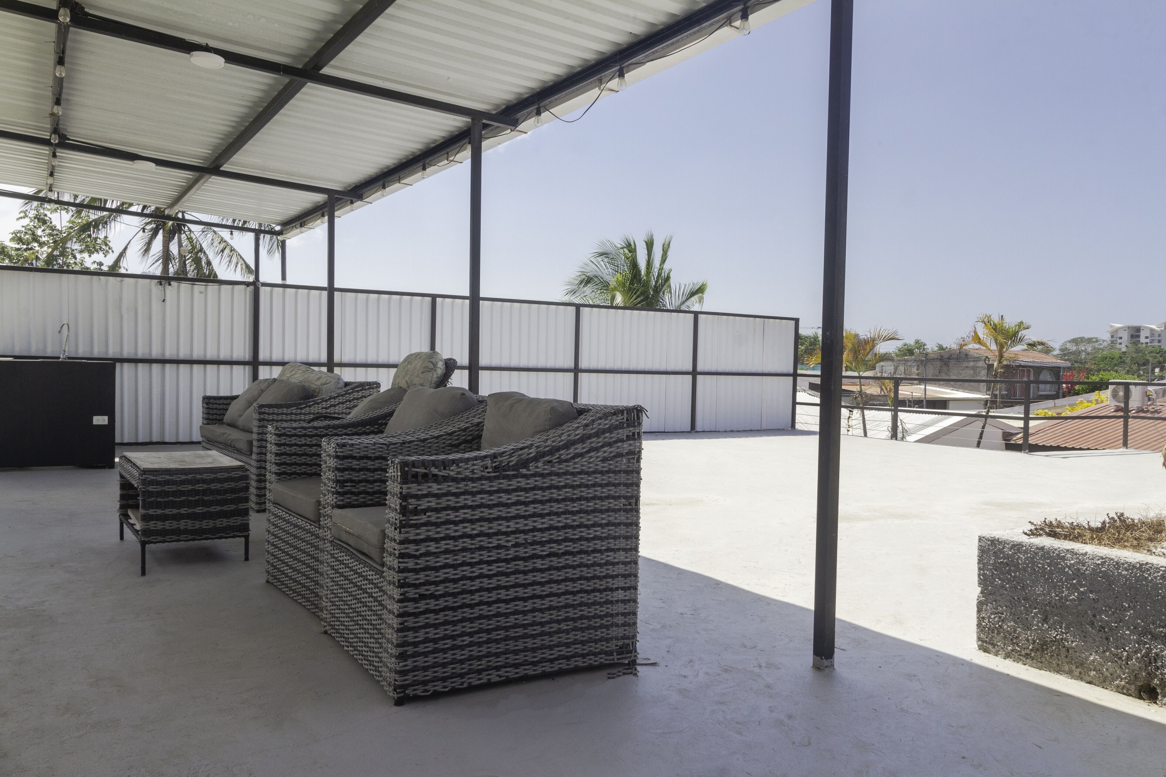 A covered outdoor seating area with wicker furniture and a concrete floor.