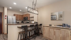 A modern kitchen with a central island, bar stools, wooden cabinets, and a microwave. - Premium Unit 2216 - One Bedroom - Zephyr Mountain Lodge 1 Condo (Winter Park)
