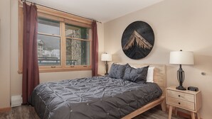 A bedroom with a large bed, two bedside tables with lamps, a wall clock, and a window with curtains. - Premium Unit 2216 - One Bedroom - Zephyr Mountain Lodge 1 Condo (Winter Park)