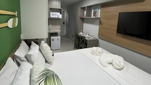 Habitación de hotel con cama, almohadas, televisor, escritorio, silla y microondas.