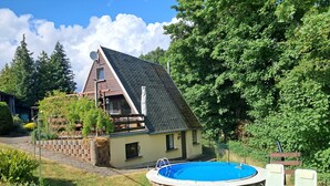 Una casa con piscina, terraza de madera y jardín.