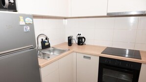 Una cocina compacta equipada con refrigerador, pileta, cafetera y horno.