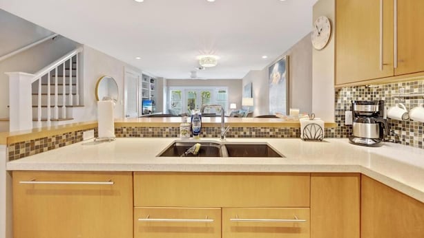 Una cocina moderna con una isla central, estanterías empotradas y un amplio ventanal.