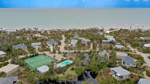 Vista aérea de una zona residencial costera con casas, una cancha de tenis y una piscina.