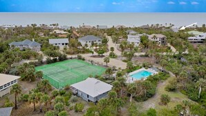Vista aérea de una zona residencial costera con casas, cancha de tenis y piscina.