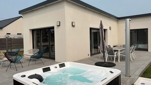 Un espace moderne aménagé à l’extérieur avec un jacuzzi, une terrasse, des chaises et une table.