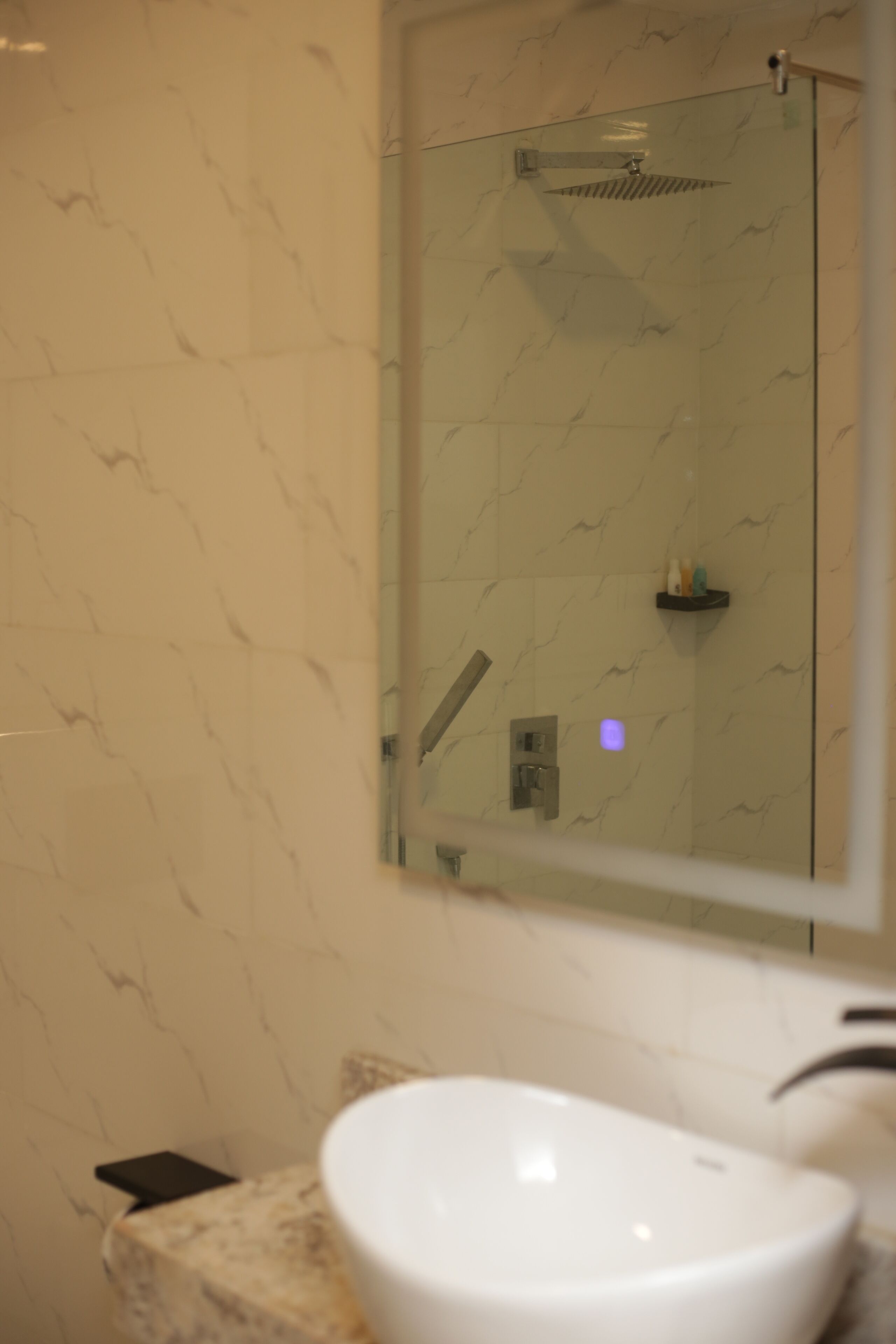 Un bagno con doccia vetro, lavandino bianco e pareti con decoro marmorizzato.