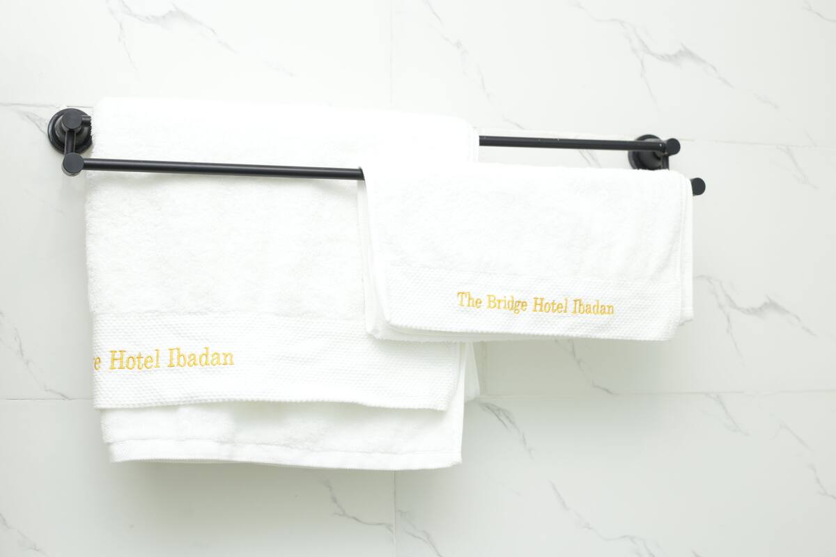 Two white towels hanging on a black towel rack against a white marble wall.