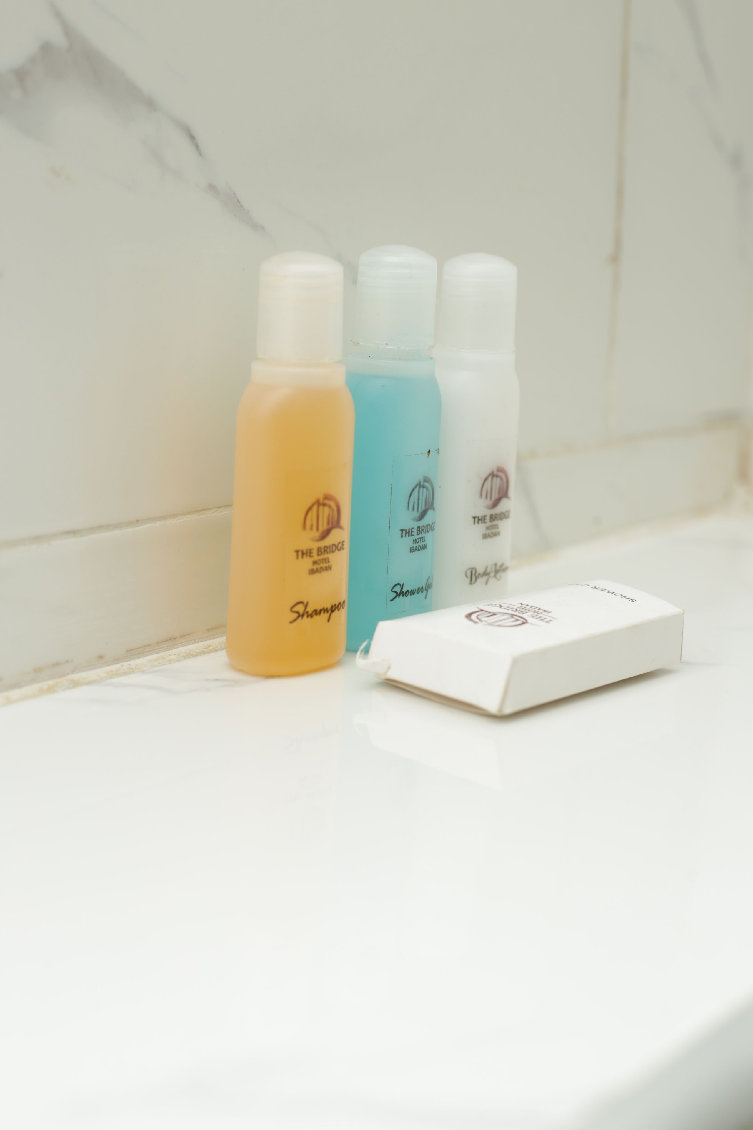 Drei Shampoo-Flaschen und eine Schachtel auf einer weißen Oberfläche.