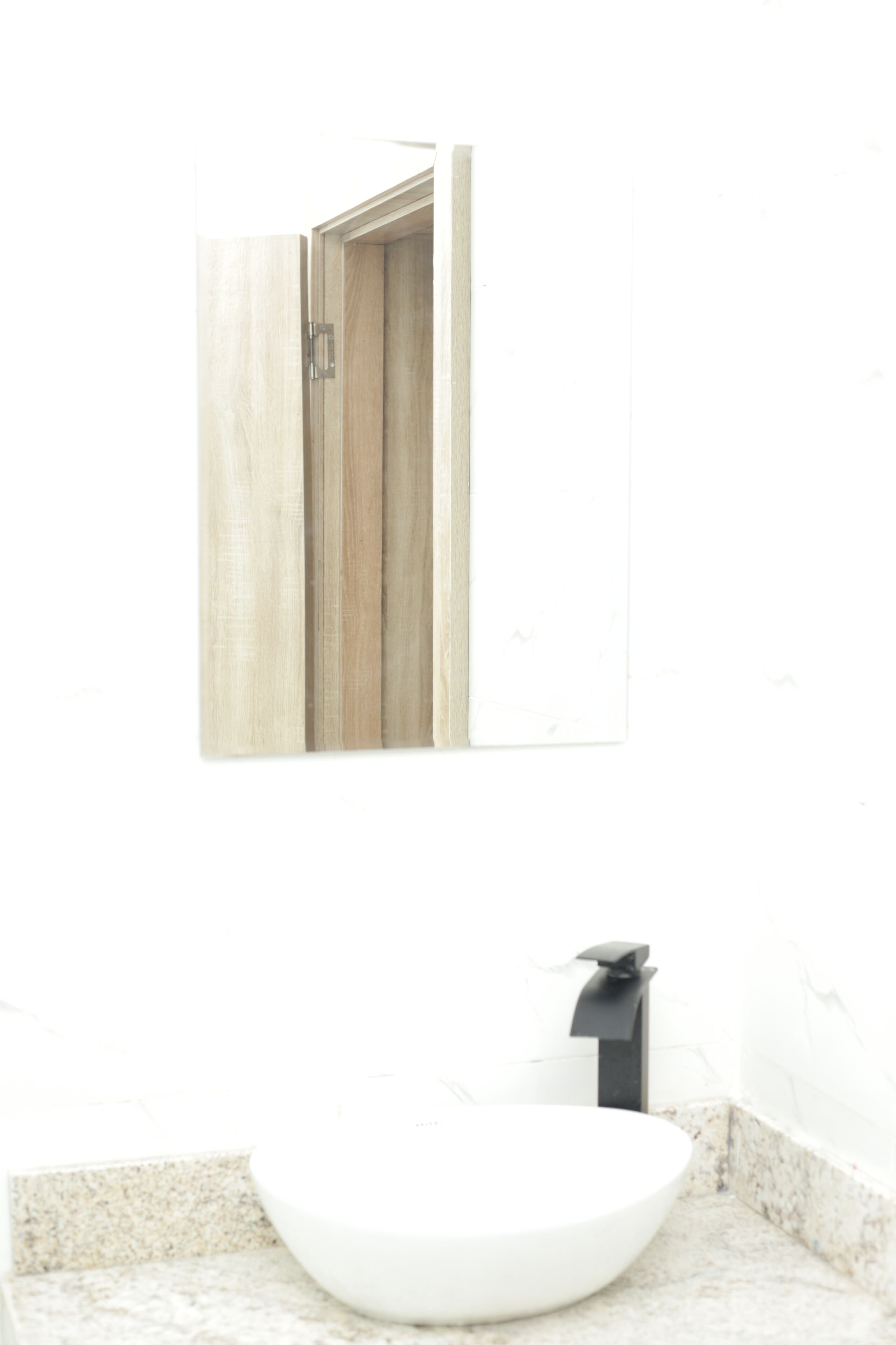 Un baño con un lavabo blanco, una puerta de madera y un espejo.