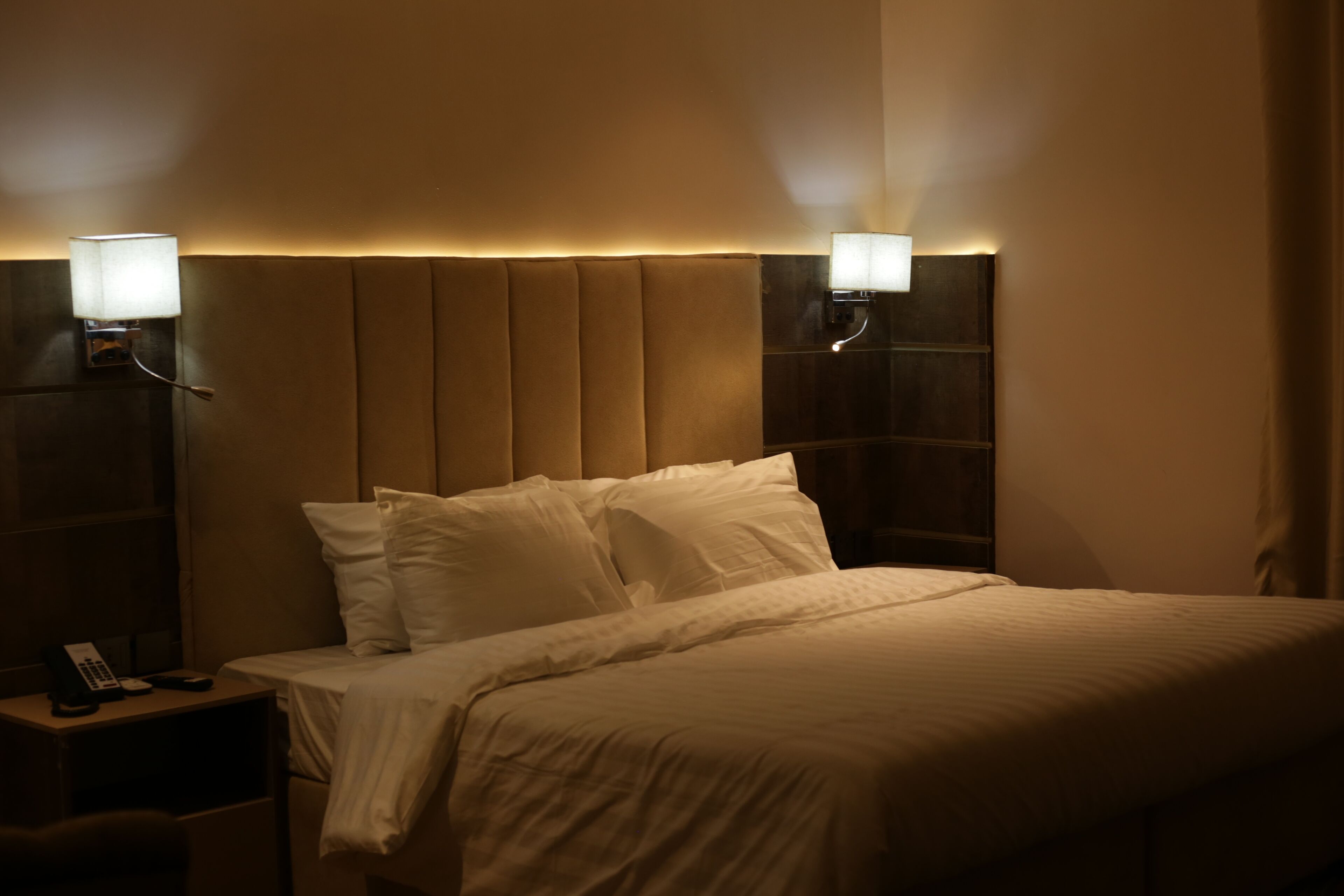Een hotelkamer met een groot bed, twee bedlampen en een nachtkastje met een telefoon.