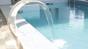 A clear water feature with a curved metal structure at the edge of a pool. - The Bridge Hotel (Ibadan)