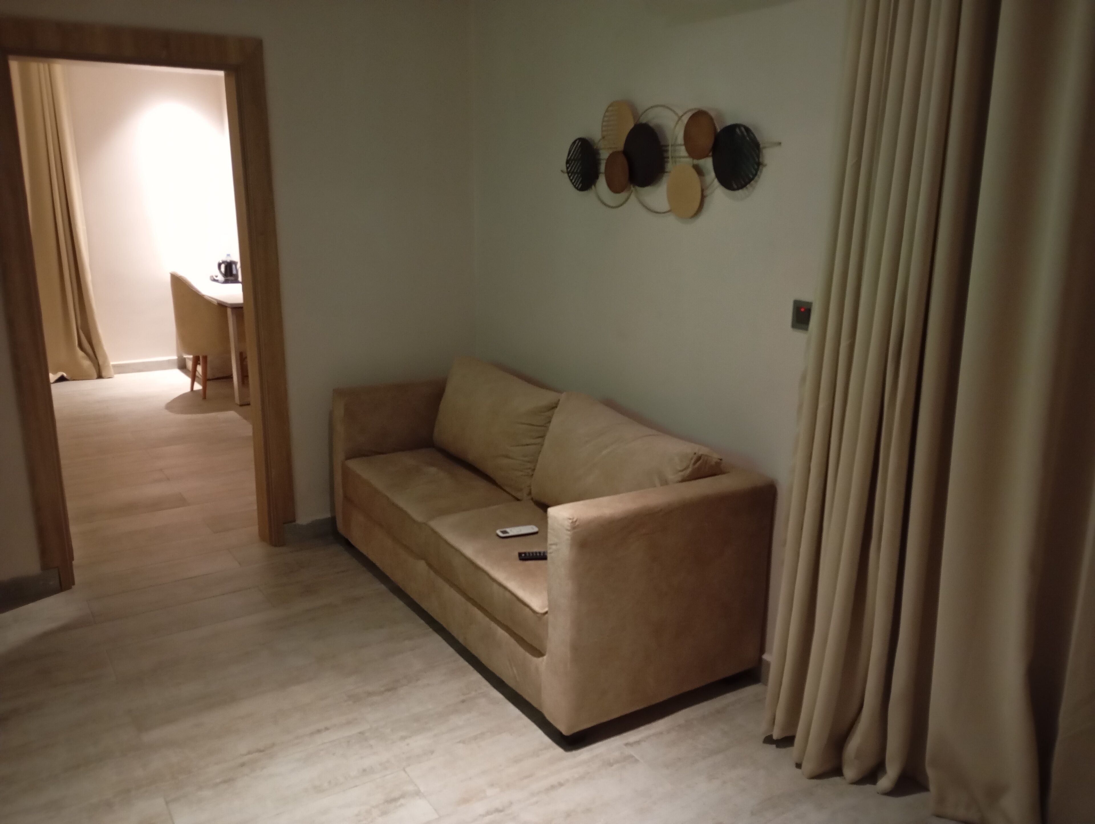 A living room with a beige sofa, a coffee table, and a wall-mounted decorative item.