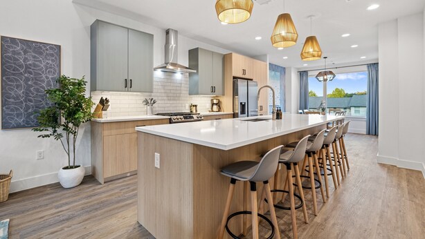A modern kitchen with a large island, bar stools, and pendant lighting.