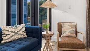A modern living room with a blue sofa, a brown leather chair, and a small wooden table with a plant.