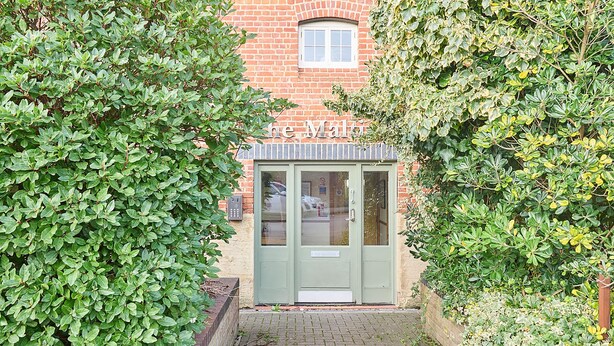 A green door with a sign above it, surrounded by dense green foliage. - Host & Stay | Roper Road (Canterbury)