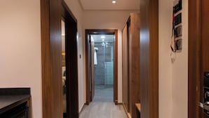 A hallway with wooden doors and a tiled floor leading to a bathroom. - RASIA HOTEL  (Jeddah)