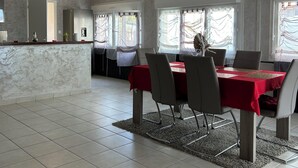 Un comedor amplio con encimera de mármol, una mesa cubierta con mantel rojo y sillas modernas.
