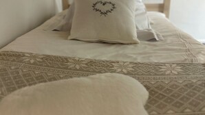 Una cama con colcha estampada y almohada con forma de corazón.