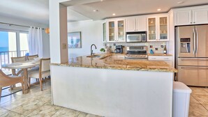 A modern kitchen with white cabinets, a stainless steel refrigerator, and a granite countertop. - ⭐Unique, Stunning Views-Fantastic Location-Land's End 9-301⭐ (Treasure Island)