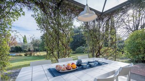 An outdoor dining area with a table set for breakfast, surrounded by greenery and a view of a garden. - Il Villino Del Collezionista With Pool In Pistoia (Pistoia)