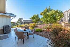 Relax in a serene outdoor space surrounded by lush greenery and a patio with a round table and four chairs.