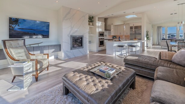 Un salon spacieux doté d’un grand téléviseur, d’une cheminée et d’un coin cuisine équipé d’appareils électroménagers modernes.