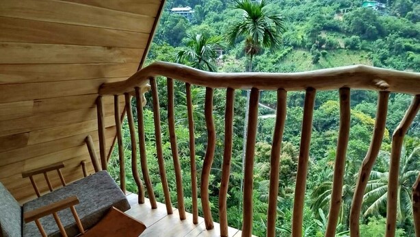 Un terrazzo in legno con vista su un verde lussureggiante e un edificio in lontananza.