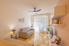 A living room with a sofa, a small table with a lamp, a ceiling fan, and a television. - La Pineta sul Mare by Wonderful Italy (Sanremo)