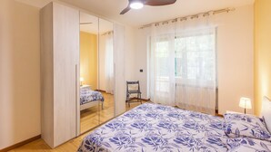 A bedroom with a bed, a chair, a wardrobe, a ceiling fan, and a window with curtains. - La Pineta sul Mare by Wonderful Italy (Sanremo)