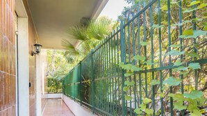 A covered corridor with tiled flooring, a green metal fence, and foliage. - La Pineta sul Mare by Wonderful Italy (Sanremo)