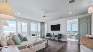 Une chambre spacieuse avec un grand lit, un bureau et une vue sur l’océan.