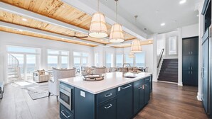 A spacious kitchen with a large island, wooden ceiling beams, and pendant lighting.