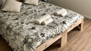 A bedroom with a wooden bed, floral bedding, a bedside lamp, and a hanging light fixture. - 1-bedroom gîte with access to covered, heated swimming pool. 2 steps from the sea  (Guissény)
