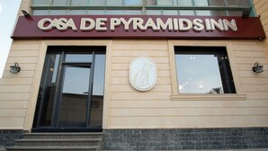 Das Äußere vom Casa de Pyramids Inn mit einem großen Schild über dem Eingang, einem Logo an der Wand und Stufen, die zur Tür führen.