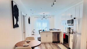 A modern kitchen with a dining area, stainless steel appliances, and a view of the outdoors.