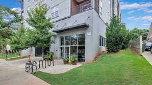A modern building with a large glass entrance, a bike parked outside, and a well-maintained lawn.