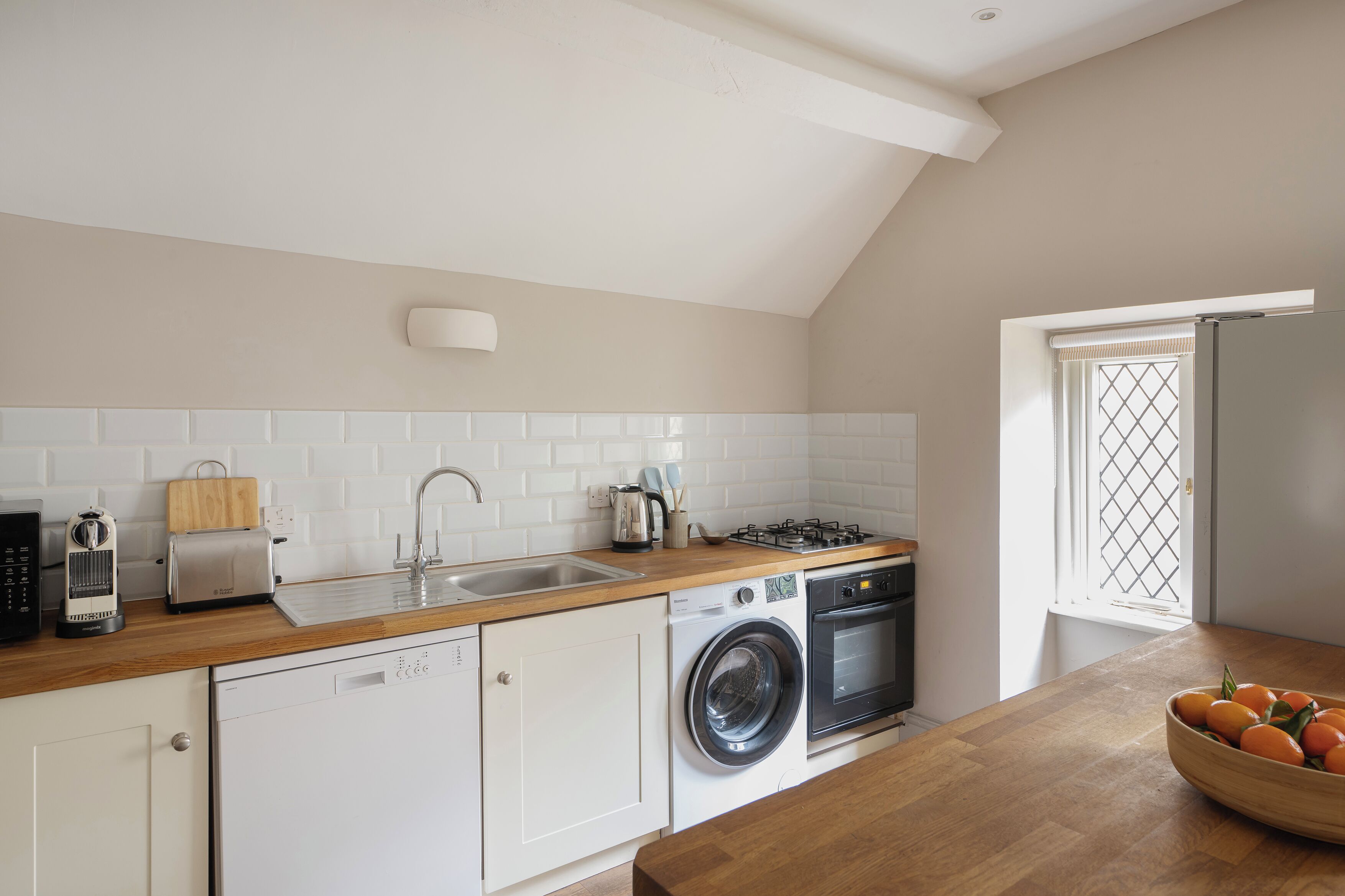 A kitchen with a wooden countertop, a washing machine, a stove, and a sink.