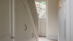 Un couloir avec un escalier, une porte et une fenêtre donnant sur un paysage verdoyant.