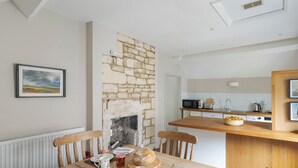 Un coin repas avec une table en bois, des chaises et une cheminée en pierre.