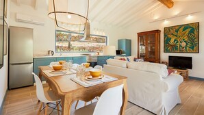 A modern kitchen with a dining area, a sofa, and a TV. - Olive Tree House - Two Bedroom Villa, Sleeps 4 (Fontelo)