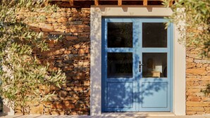 A stone wall with a blue door, a tiled roof, and a window. - Olive Tree House - Two Bedroom Villa, Sleeps 4 (Fontelo)